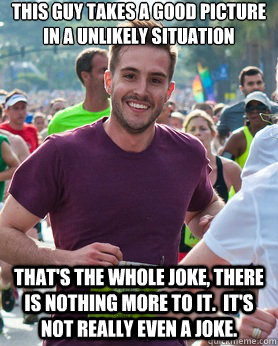 This guy takes a good picture in a unlikely situation That's the whole joke, there is nothing more to it.  It's not really even a joke.  Ridiculously photogenic guy